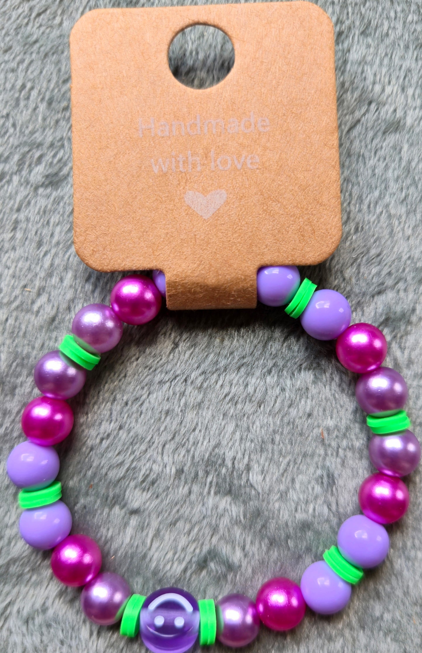 Purple, pink and green beaded bracelet with a smiley face